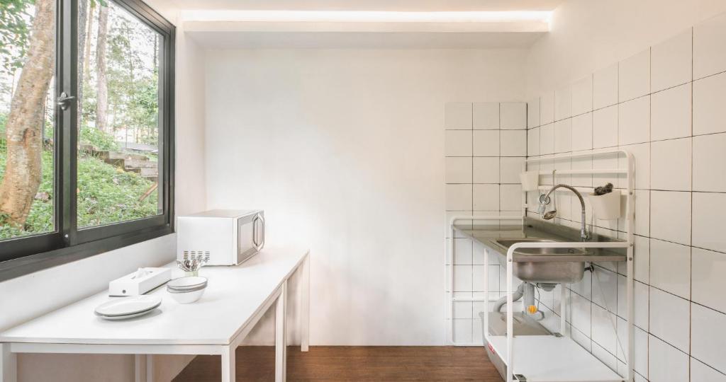 a white kitchen with a sink and a microwave at Bobocabin Pacet, Mojokerto in Claket