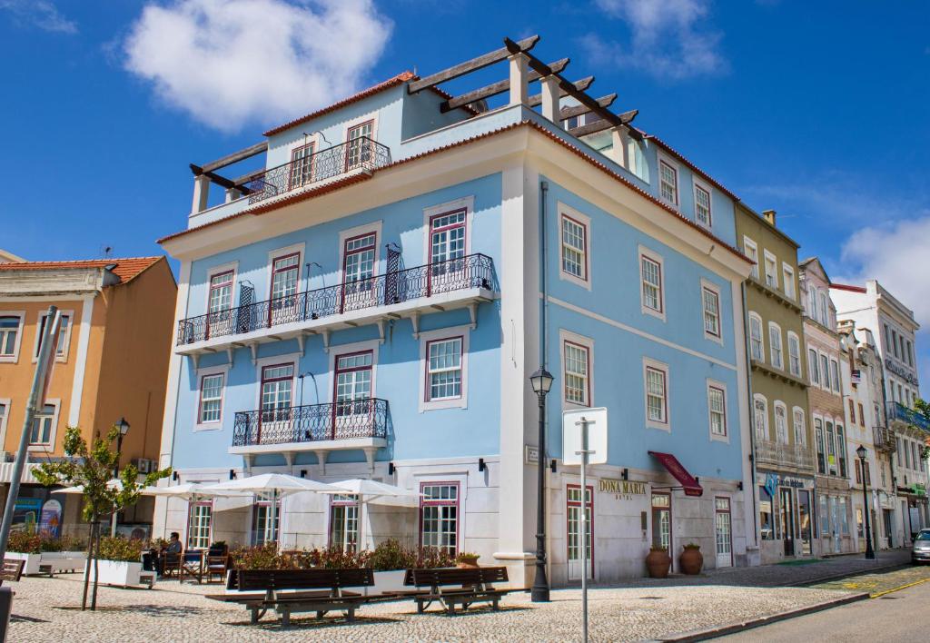 Dona Maria Hotel في فيغيورا دا فوز: مبنى باللونين الأزرق والأبيض مع مقاعد أمامه