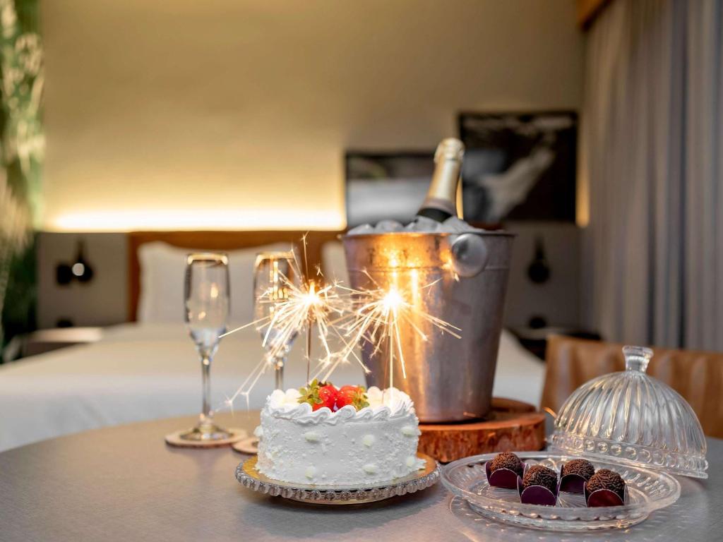 a table with a cake and a bottle of champagne and cupcakes at Grand Mercure SP Itaim Bibi in Sao Paulo