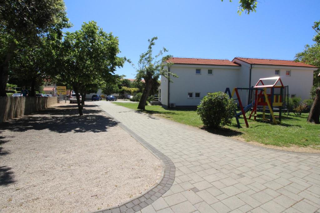 a brick walkway in a park with a playground at Villas Corinthia in Baška