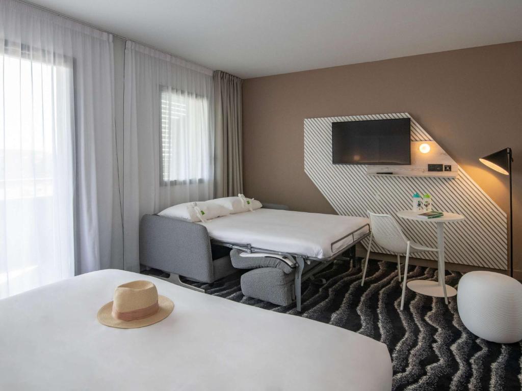 a room with a bed and a table with a hat at ibis Styles Porto Vecchio in Porto-Vecchio