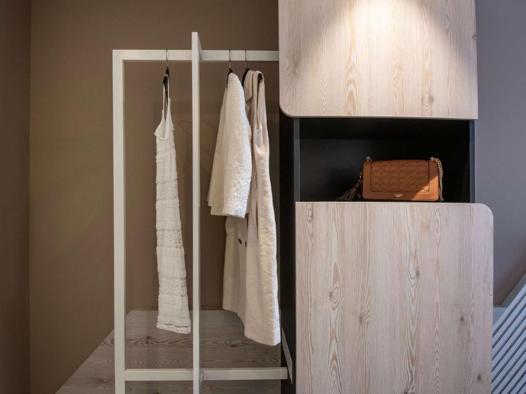 a wardrobe with white clothes and a bag in a room at ibis Styles Porto Vecchio in Porto-Vecchio