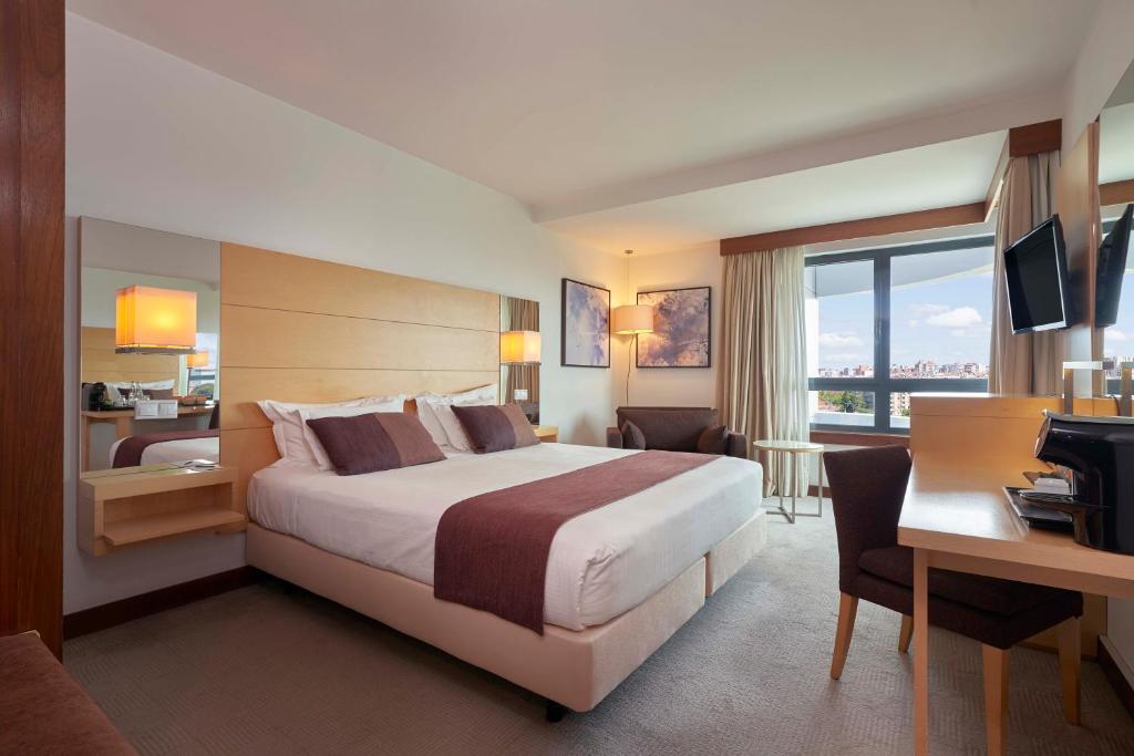 ein Hotelzimmer mit einem großen Bett und einem Schreibtisch in der Unterkunft Hotel Acores Lisboa in Lissabon
