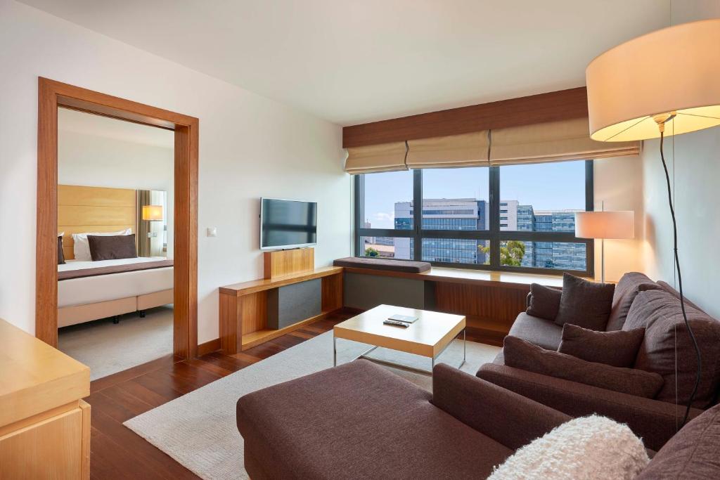 A furnished sitting room with a television, sofa and bedroom visible through an interior doorway.
