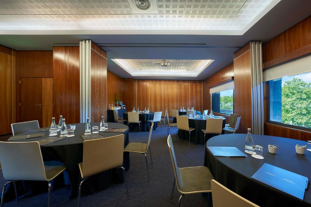 A wood-panelled meeting room with several round tables prepared for a group event.