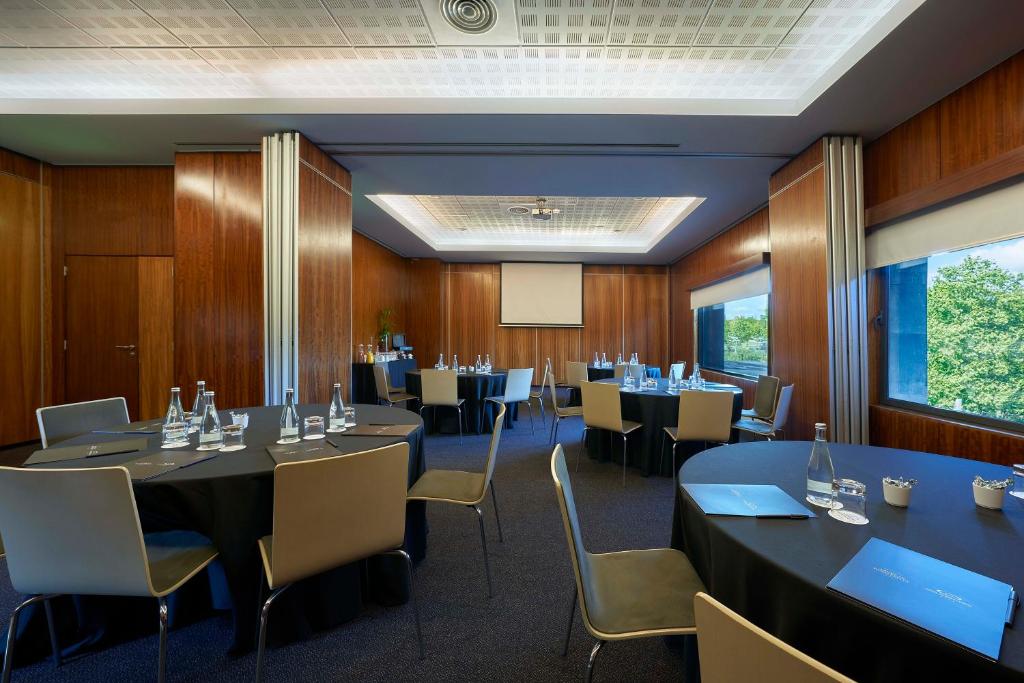 A larger conference room arranged in several round-table groups with a projection screen.