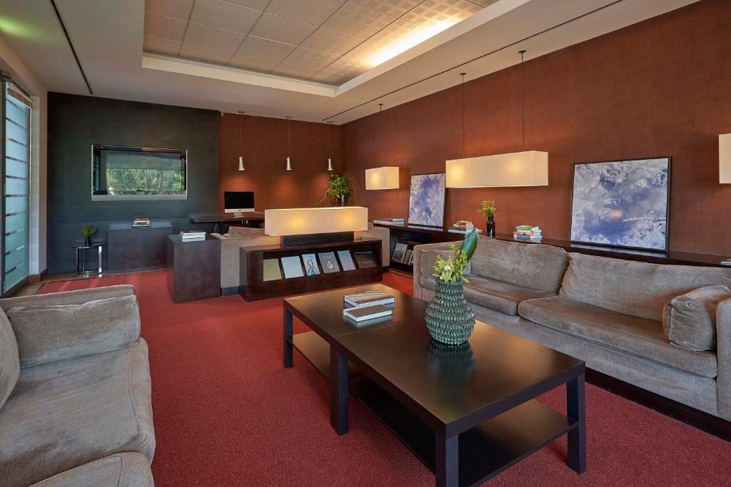 A warm, carpeted sitting room with sofas, a coffee table, lamps, and a small reception counter.