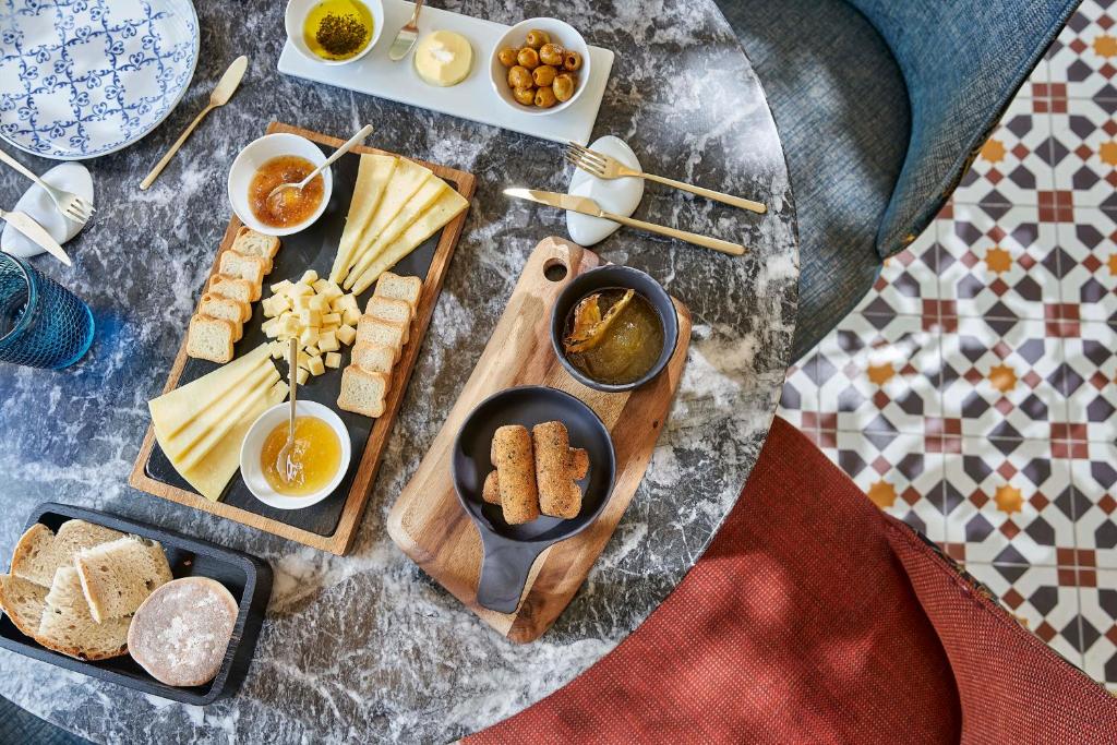 A close overhead view shows a cheese, bread and preserves spread arranged on a marble-look dining table.