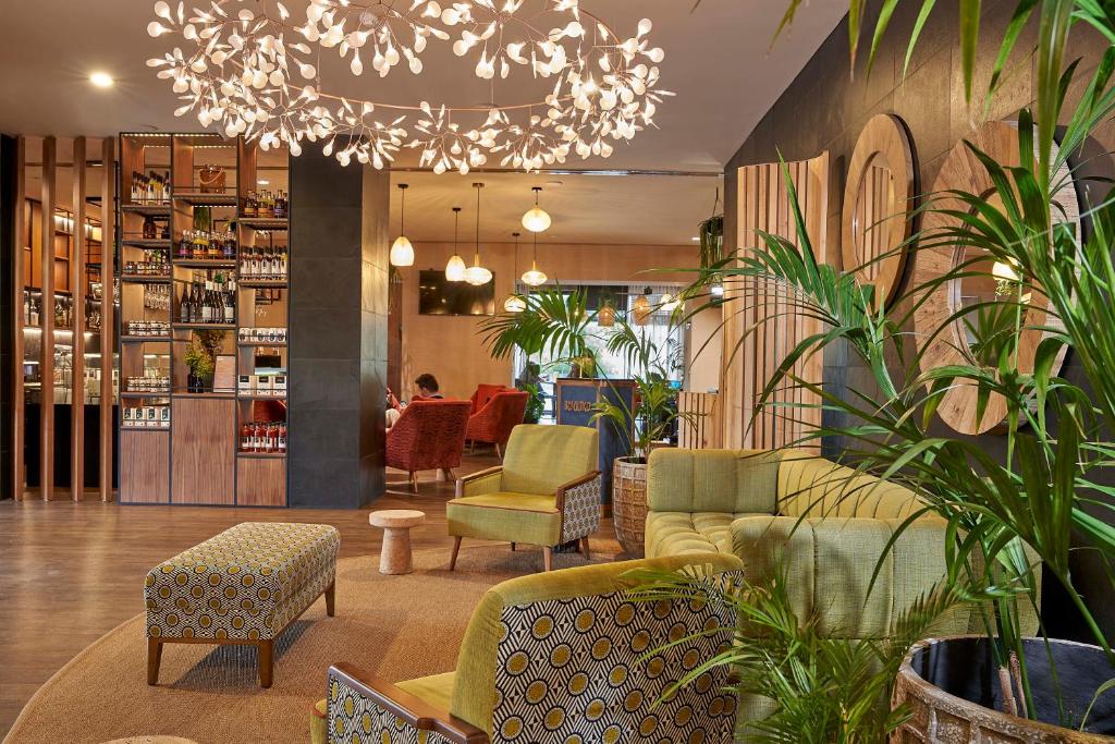 A lively lobby lounge with patterned seating, plants and a decorative chandelier.