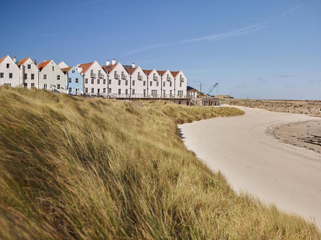szereg domów siedzących na szczycie plaży w obiekcie Braye Beach Hotel w mieście Braye