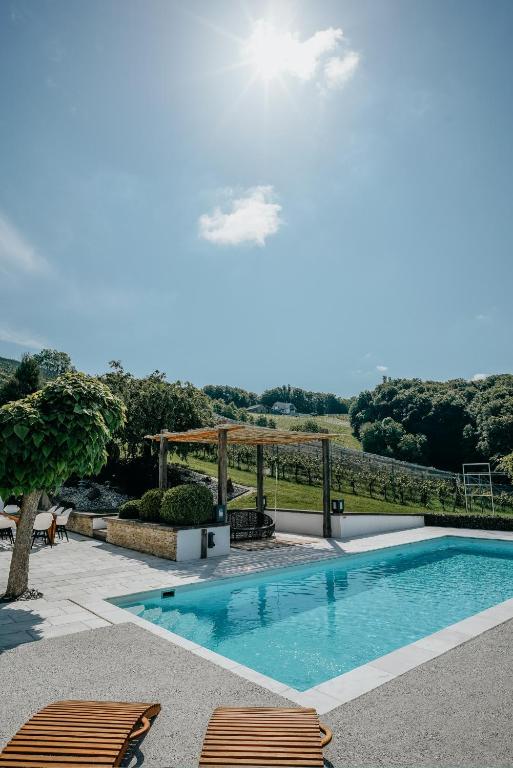 a swimming pool with two chairs and a table at Weingut Holler Chalet Weingarten in Spielfeld