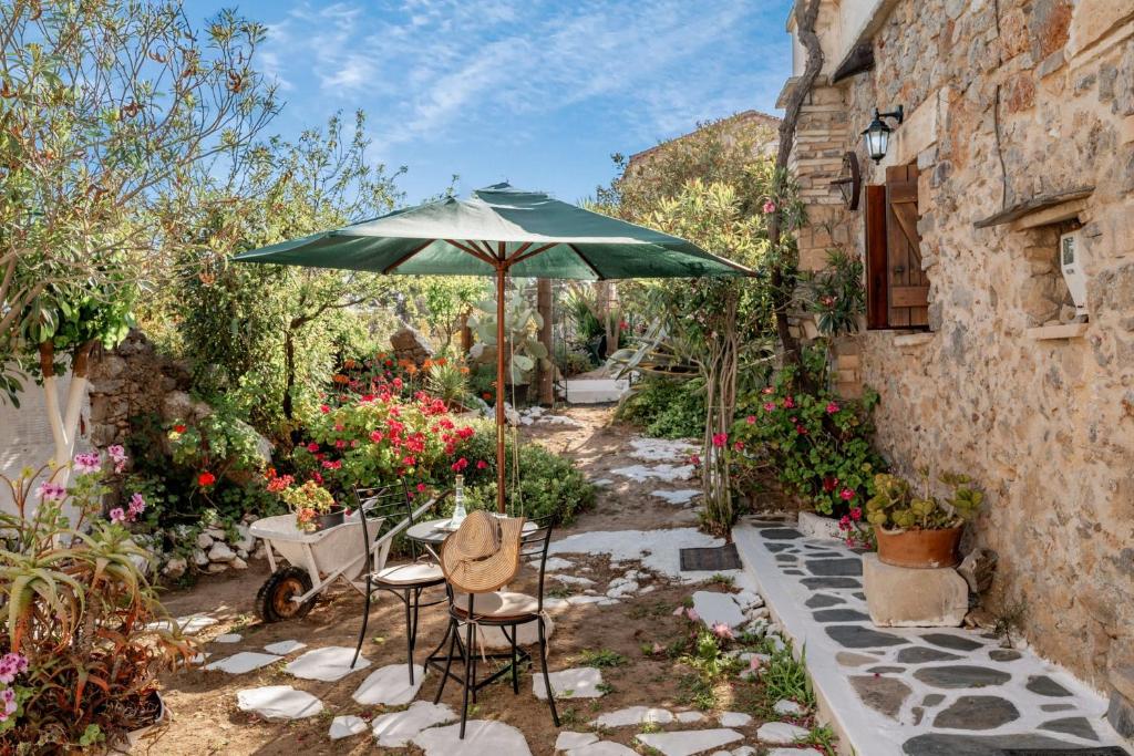 a patio with an umbrella and chairs and flowers at Agapi's Charming Retreat - Rustic Escape By Chania in Maláxa