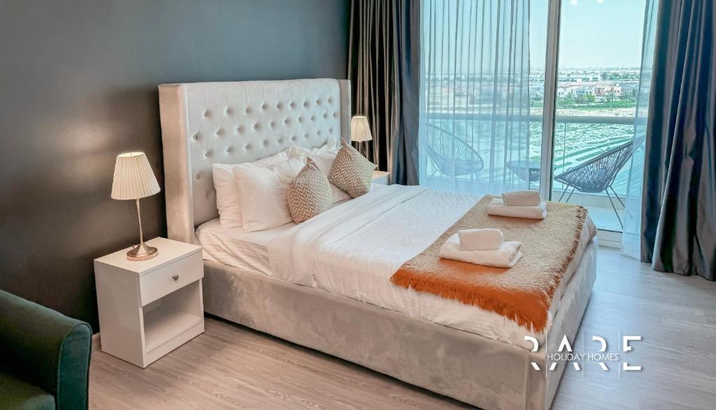 Schlafzimmer mit einem großen Bett und einem Balkon in der Unterkunft Rare Holiday Homes - Studio in Crescent Tower near City Center Mall - R712 IMPZ in Dubai