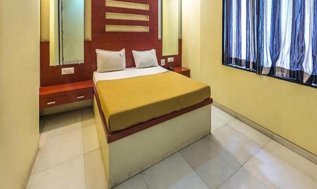 um quarto com uma cama num quarto com janelas em FabHotel Skylark Inn em Nashik
