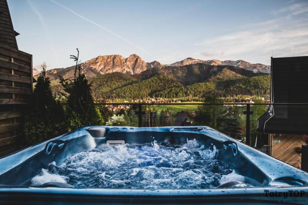 niebieska wanna wypełniona wodą na tle gór w obiekcie Czarne Wierchy jacuzzi - Luxury Chalets Kościelisko w mieście Kościelisko