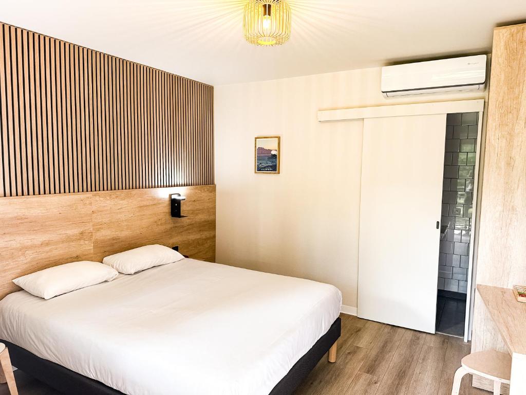 1 dormitorio con cama blanca y ventana en Hôtel Ecochic - Mont-de-Marsan, en Saint-Pierre-du-Mont