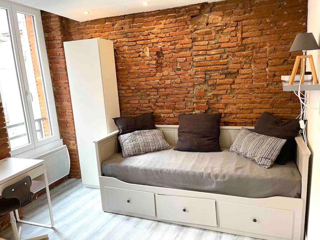 un lit dans une chambre avec un mur de briques dans l'établissement Toulouse-Cyprien, typique à 10' Capitole & Carmes, à Toulouse
