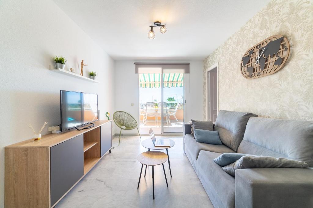 a living room with a couch and a tv at TrendyHomes Puerto - Vistas al mar, parking incluido, playa a un paso in Aguadulce