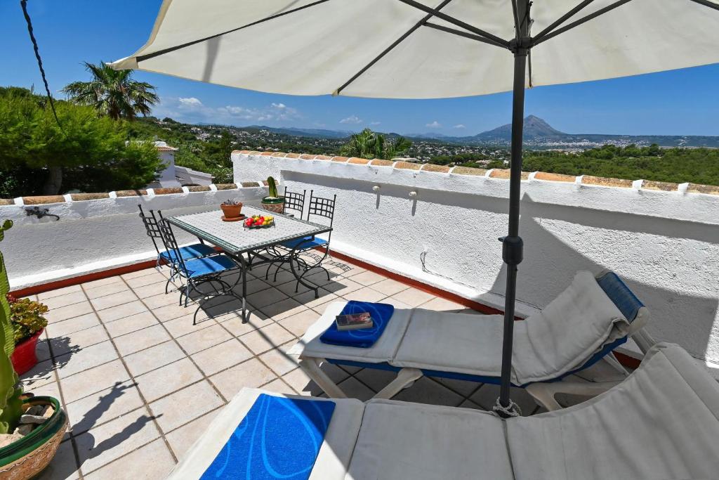 une terrasse avec une table, des chaises et un parasol dans l'établissement Casa Que Sera, à Jávea