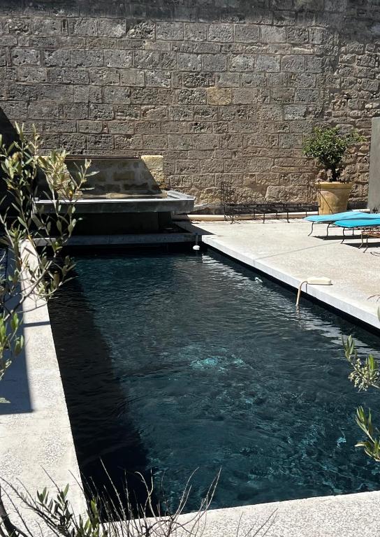 un bassin d'eau à côté d'un mur de briques dans l'établissement Maison exceptionnelle esprit loft avec piscine, à Pézenas