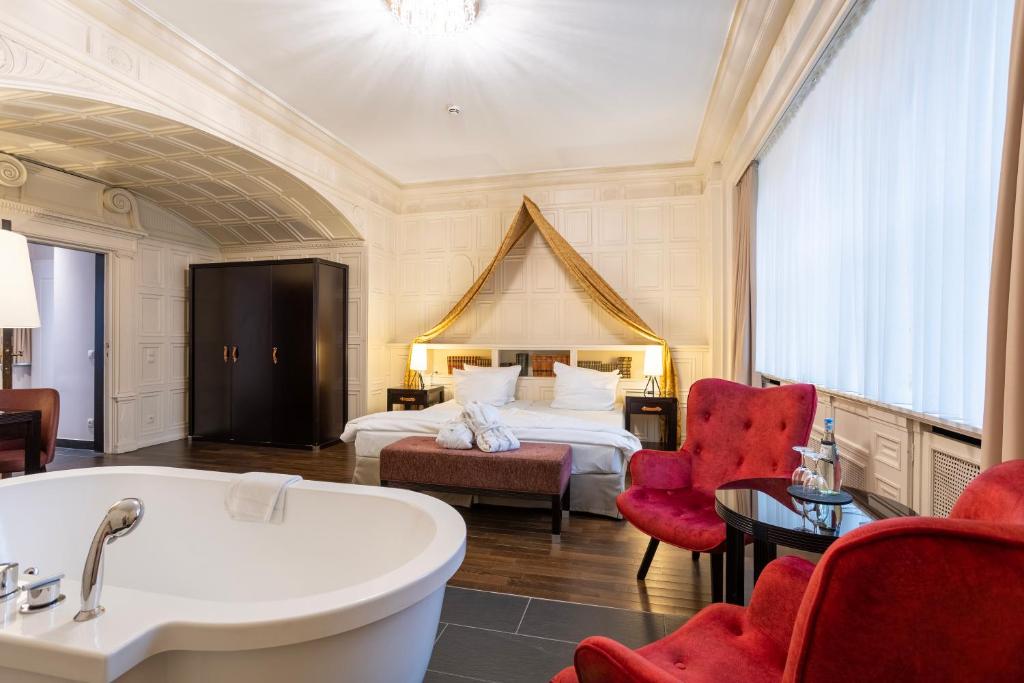 um quarto de hotel com uma banheira e uma cama em Batschari Palais Baden-Baden em Baden-Baden