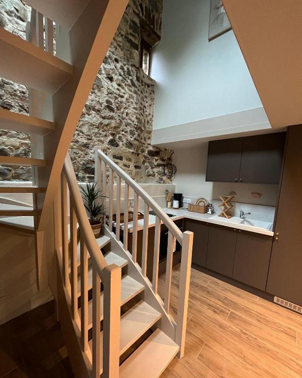 Un escalier mène à une cuisine avec un mur en pierre. dans l'établissement Le Moulin de Blanchelande, à Neufmesnil