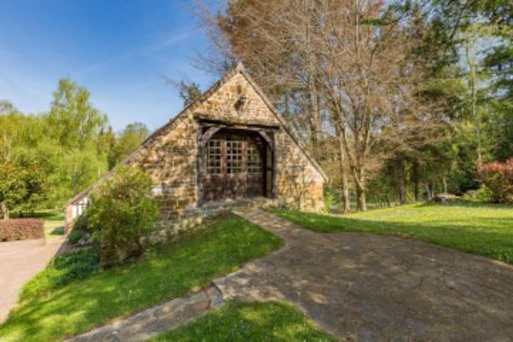 a stone building with a door in the grass at Epicéas, piscine, tennis, lac in Guerquesalles