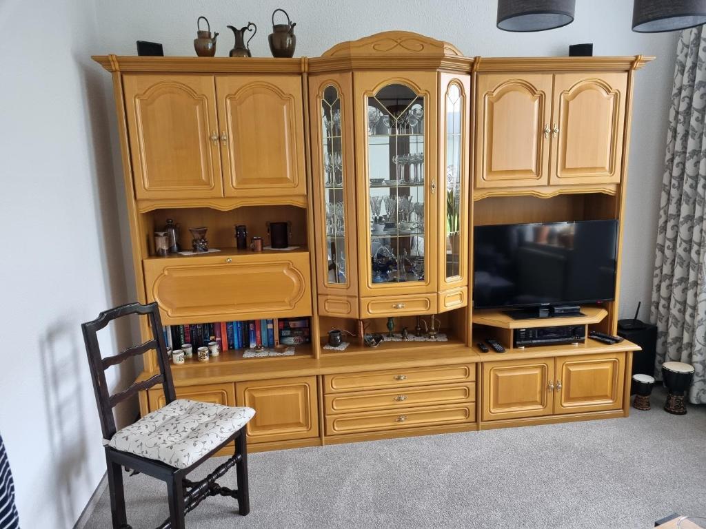 a wooden entertainment center with a television and a chair at Ferienwohnung Romy Müller in Mohlsdorf