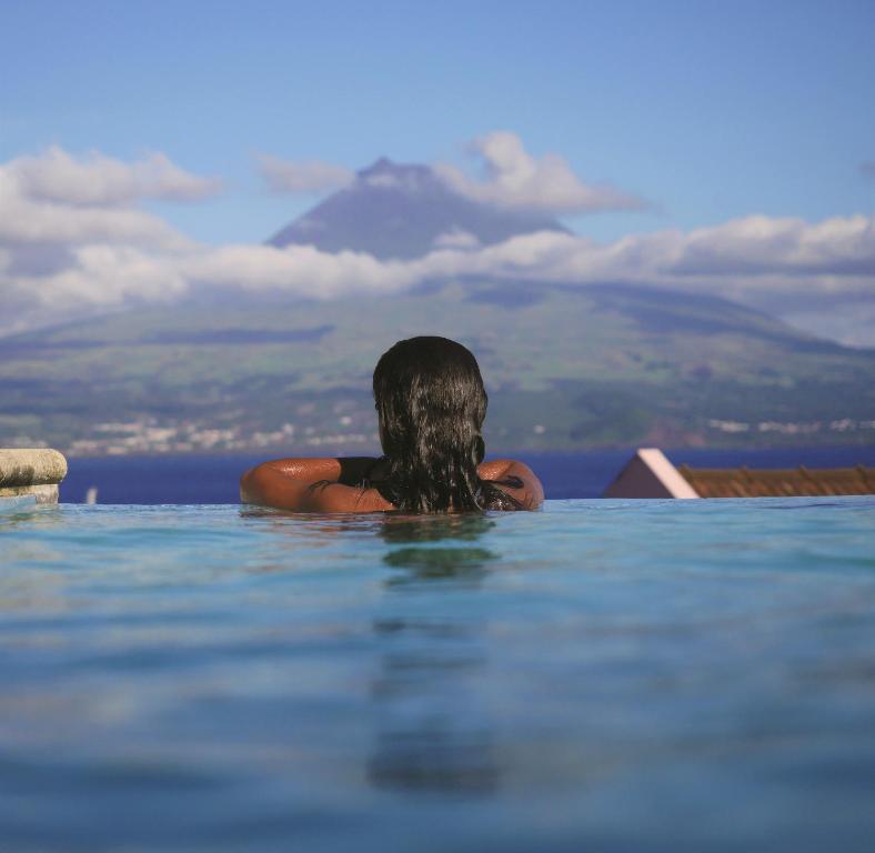 una mujer sentada en el agua en una piscina en Azoris Faial Garden – Resort Hotel en Horta