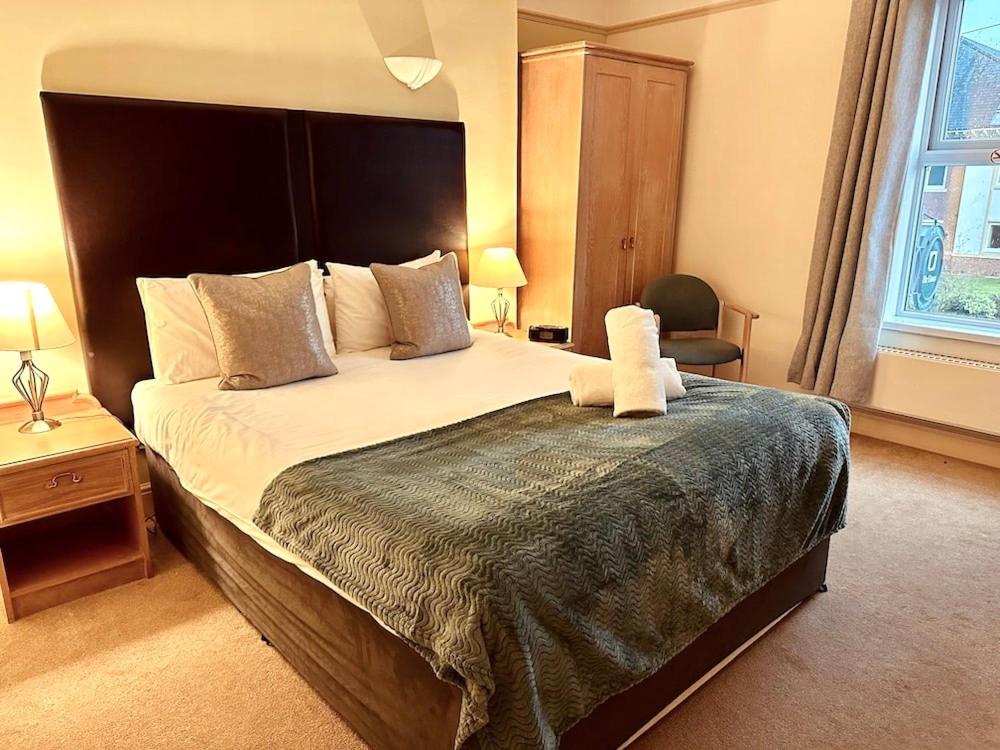 a bedroom with a large bed with a teddy bear on it at The Limes Hotel in Stratford-upon-Avon
