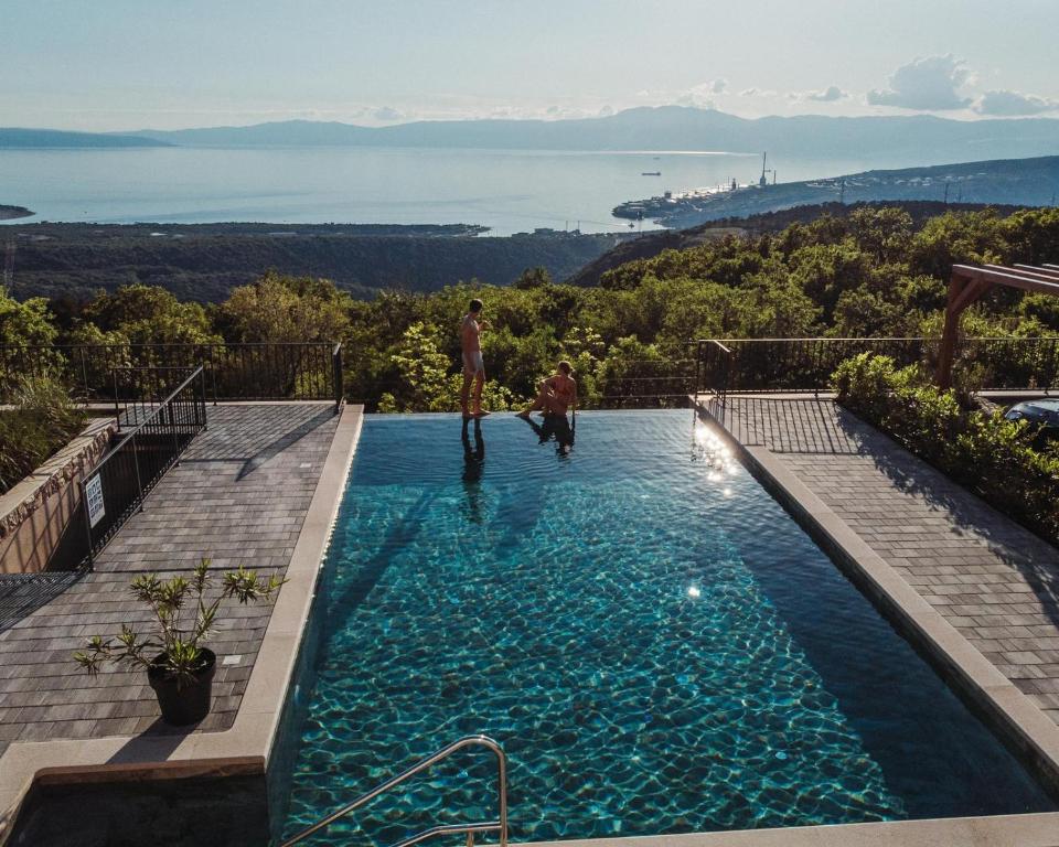 two men standing in a swimming pool with a view at Villa Green Garden - Infinity Pool, Jacuzzi, Sauna and Panoramic Sea View in Hreljin