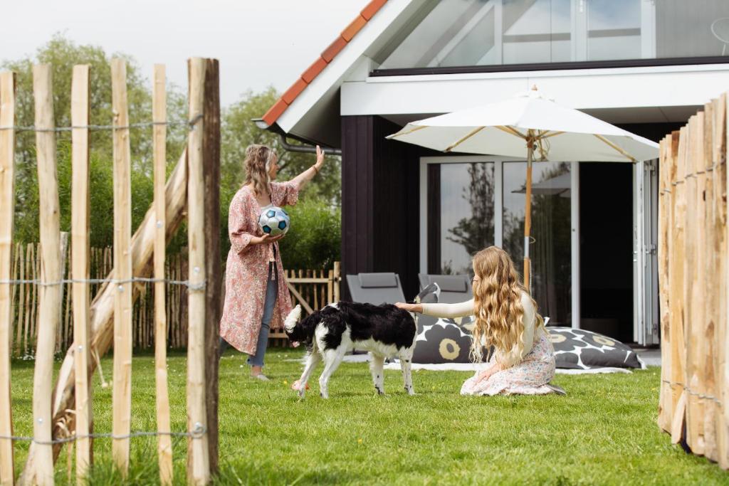 una niñita jugando con un perro en un patio en Vakantiehuis met omheinde tuin, en Dokkum