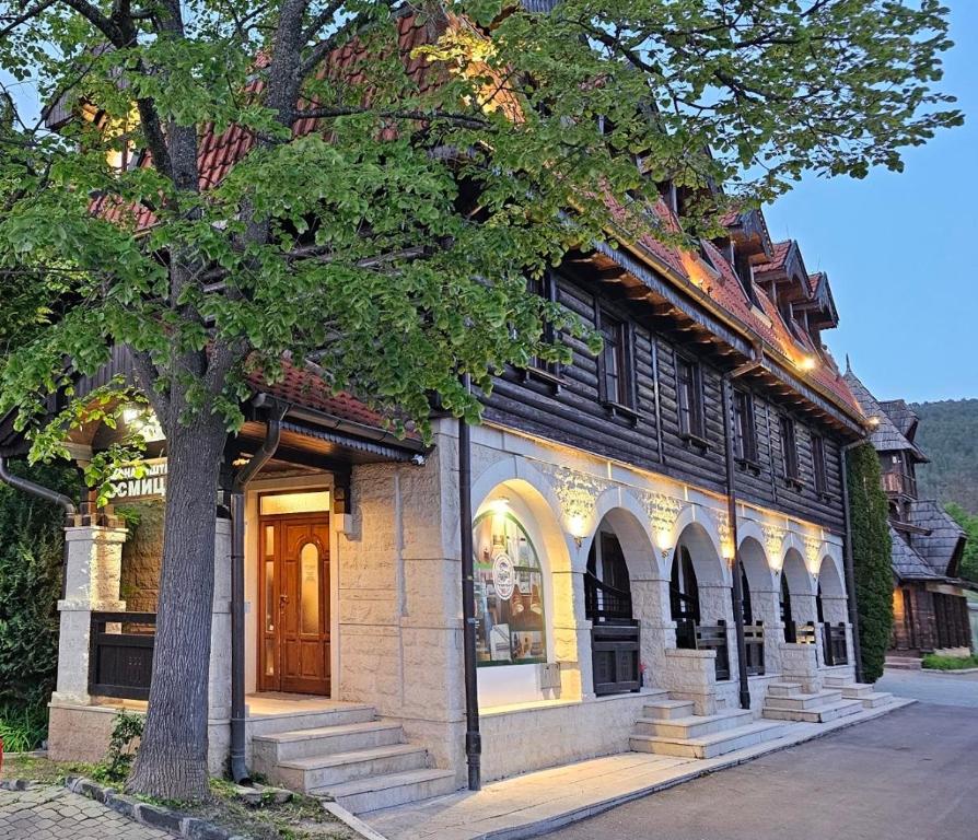 un edificio con un árbol delante de él en Konačište Osmica, en Mokra Gora