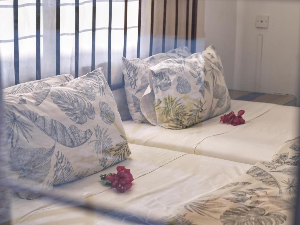 un letto con due cuscini e fiori rossi sopra di Golentle Home Stay a Maun