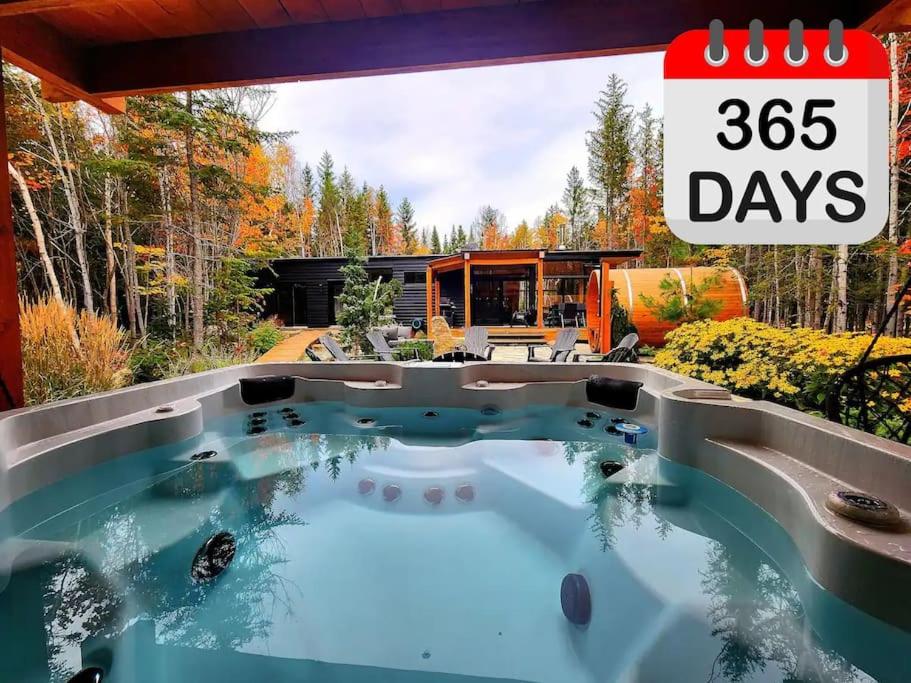 a house with a hot tub in the middle of a yard at ONИEA l Sauna & Spa in Petite-Rivière-Saint-François