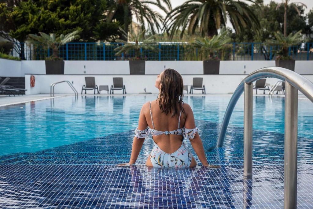 una mujer en bikini sentada en una piscina en Azoris Royal Garden – Leisure & Conference Hotel en Ponta Delgada