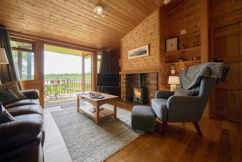 sala de estar con sofá, silla y chimenea en Egret Lodge with Hot-tub, en Carlisle