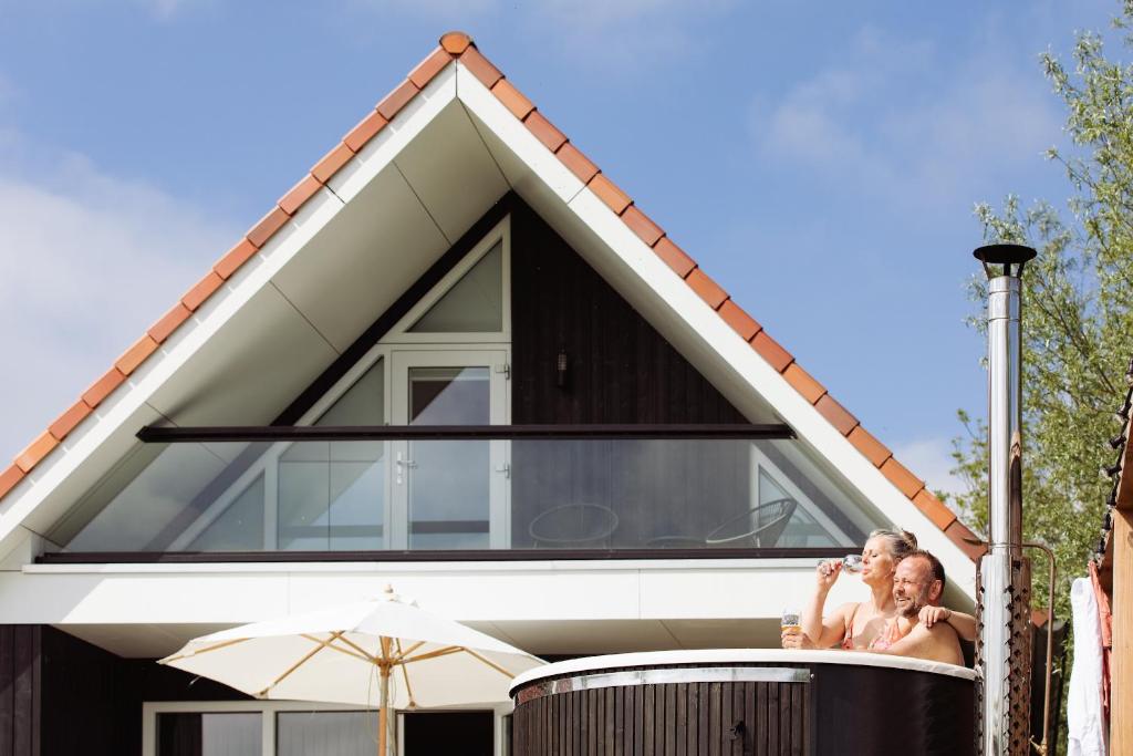 a bride and groom sitting on the edge of a house at Vakantiehuis aan het water met hottub in Dokkum