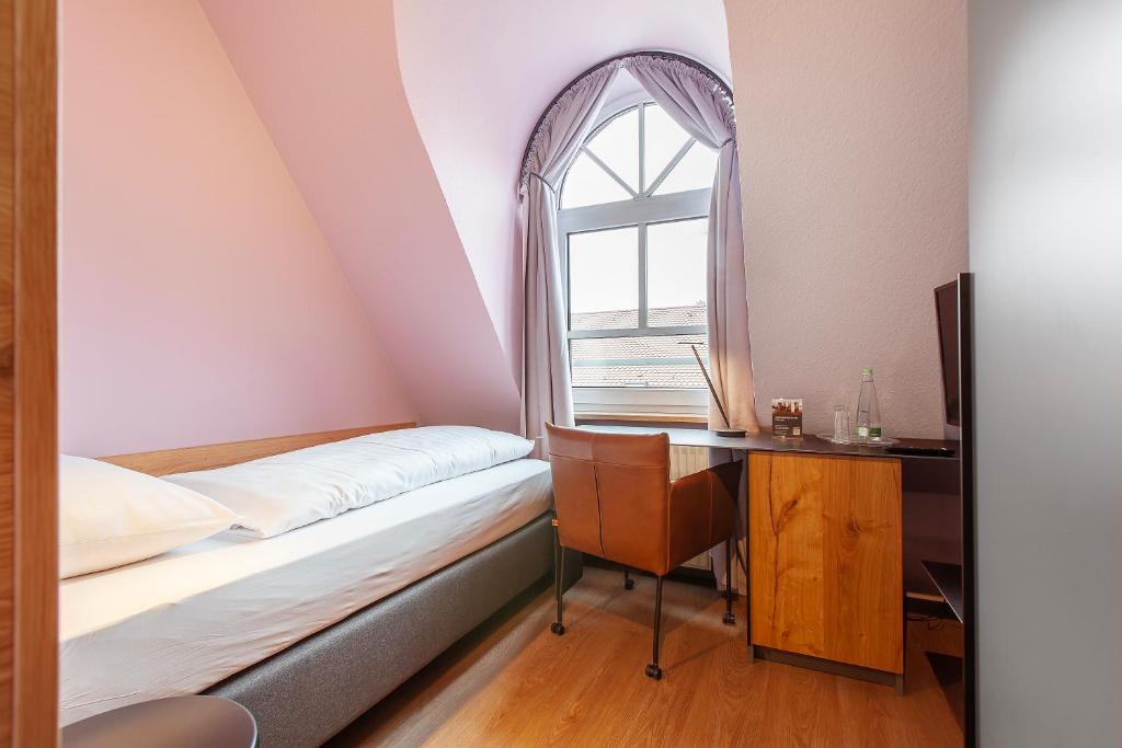 a bedroom with a bed and a desk and a window at Hotel am Jakobsmarkt in Nuremberg