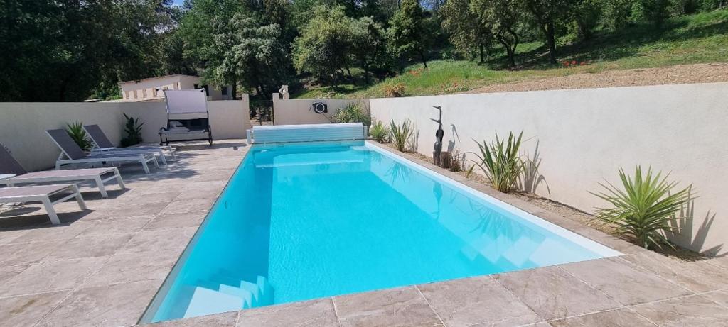 une grande piscine bleue à côté d'un mur blanc dans l'établissement Appartement N° 1 avec jardin privé LES BOIS DE ZOLA, à Saint-Estève-Janson