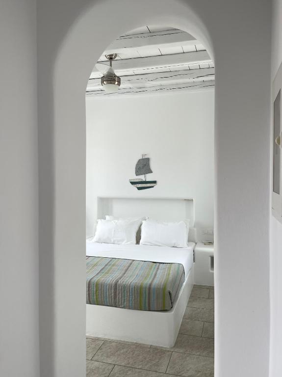 a bedroom with a white bed and an archway at MAGGANARI MOMENTS 2 in Manganari