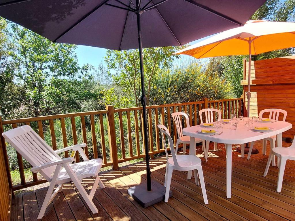 une table et des chaises sur une terrasse avec des parasols dans l'établissement Maison climatisée 5 pers avec terrasse, parking, WiFi, et équipements complets dans quartier calme - FR-1-382-129, à Grospierres