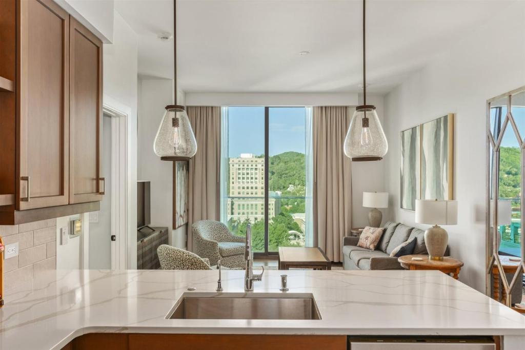 a kitchen with a sink and a living room at 'The Views Over Pack Square Park' A Luxury Downtown Condo with Mountain and City Views at Arras Vacation Rentals in Asheville