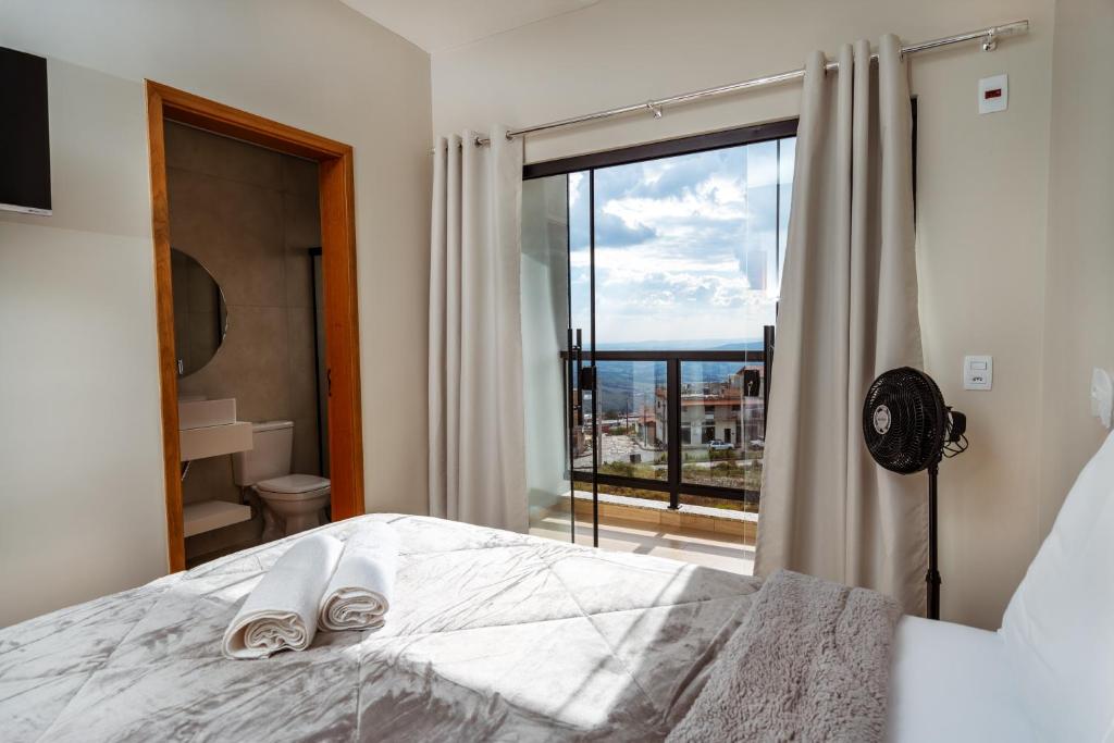 a bedroom with a bed and a large window at Pousada Canto da Montanha in São Thomé das Letras