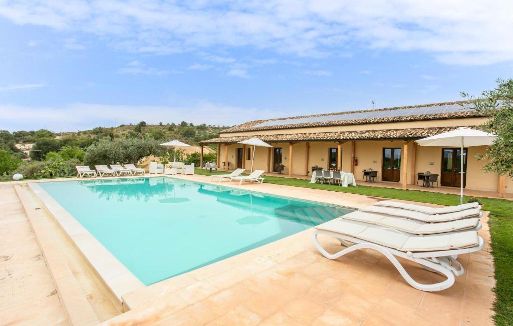 une villa avec une piscine et des chaises longues dans l'établissement Oriental Muti, à Chiaramonte Gulfi