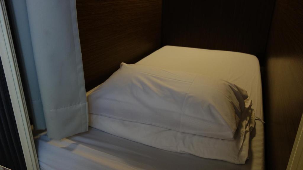 Lanyu Blue Capsule في Lanyu: سرير صغير ومخدة بيضاء في الغرفة