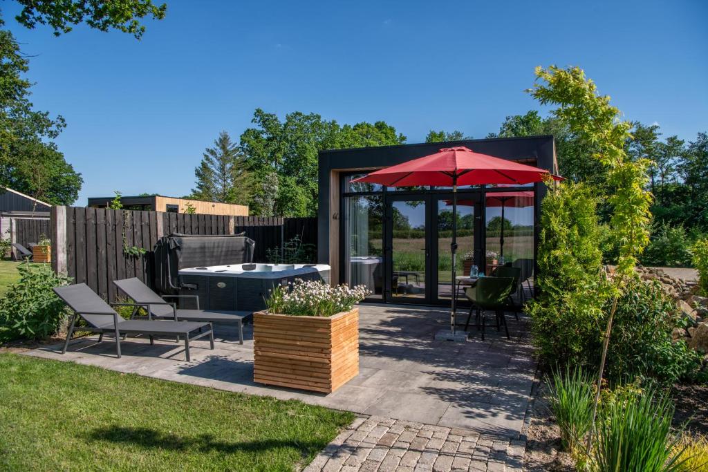 a patio with a table and a red umbrella at Wellnesslodge Specht in Dalerveen