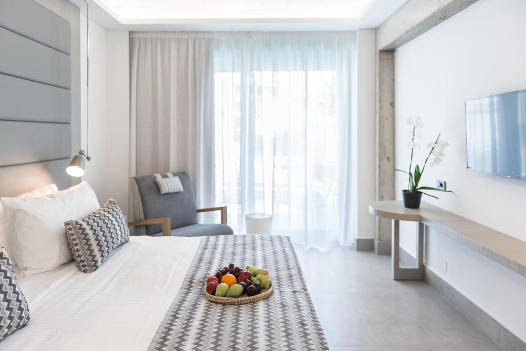 a hotel room with a bowl of fruit on a bed at Glaros Beach Hotel in Hersonissos