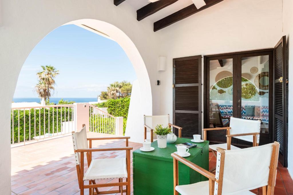 een terras met een groene tafel en stoelen en de oceaan bij Bini Luna - Binibeca Vell in Binibeca