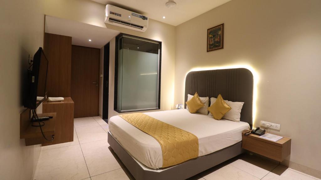 um quarto de hotel com uma cama e uma televisão em Hotel The UBE Residency em Mumbai